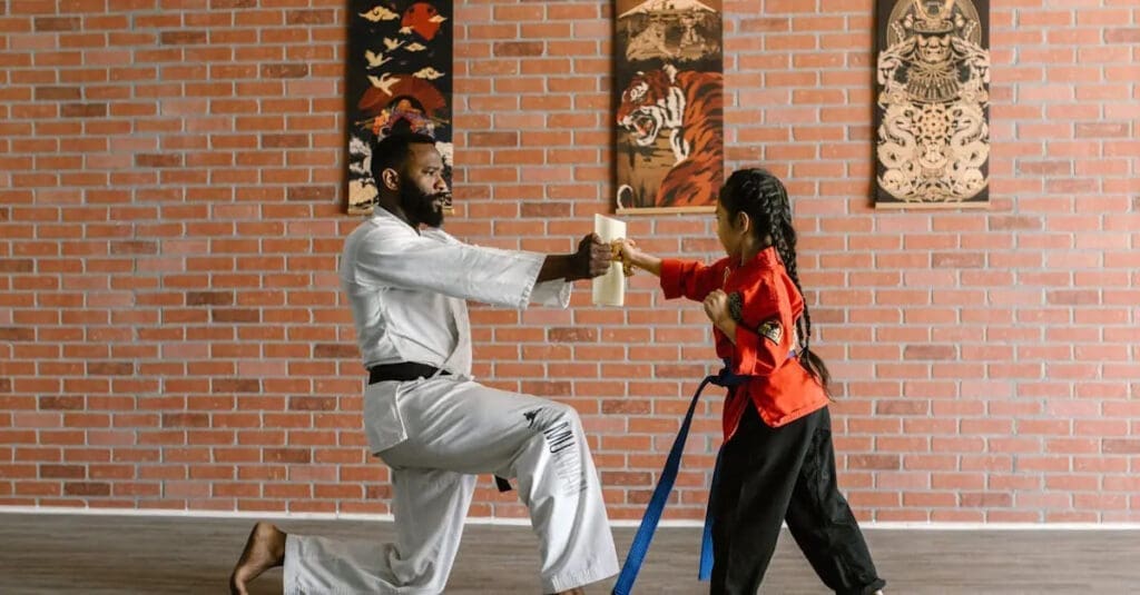 Instructor guiding a young student through martial arts basics during class