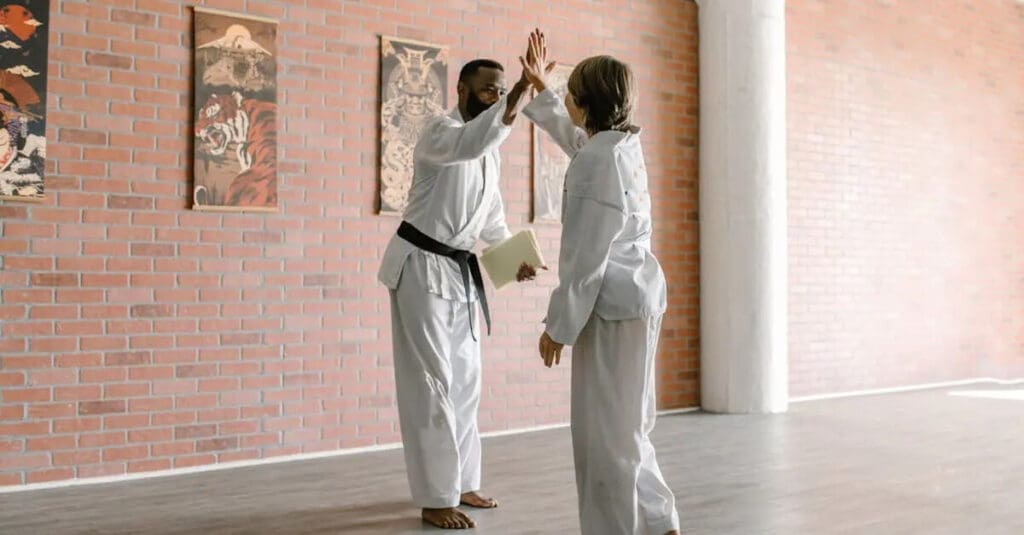 Instructor high-fiving a student after practice in a martial arts for beginners class