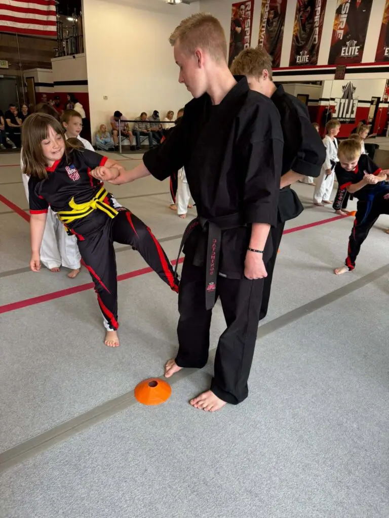 Young martial arts students practicing controlled kicks and partner drills with an instructor in a training class setting + martial arts etiquette for beginners